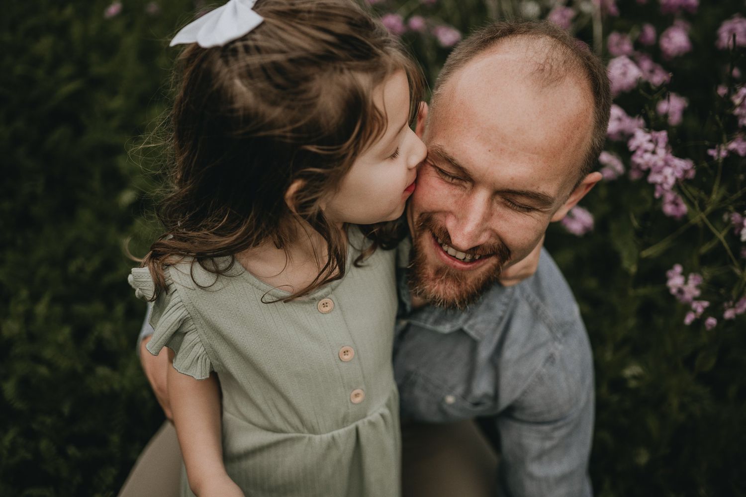 A tender moment captured in a garden with pink blossoms as a heartwarming display of family affection.