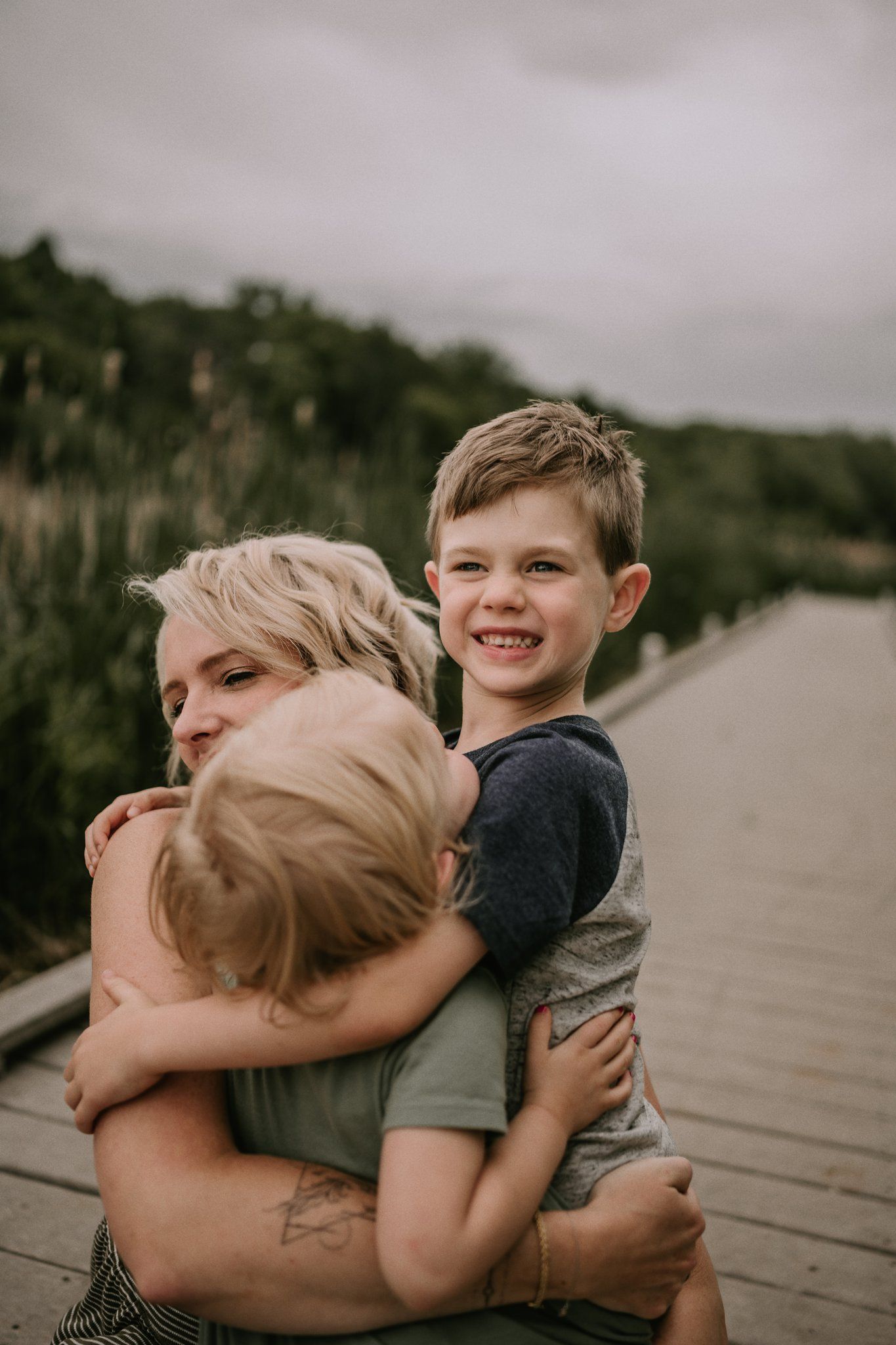 Joyful cuddles shared on a wooden walkway overlooking natural scenery.