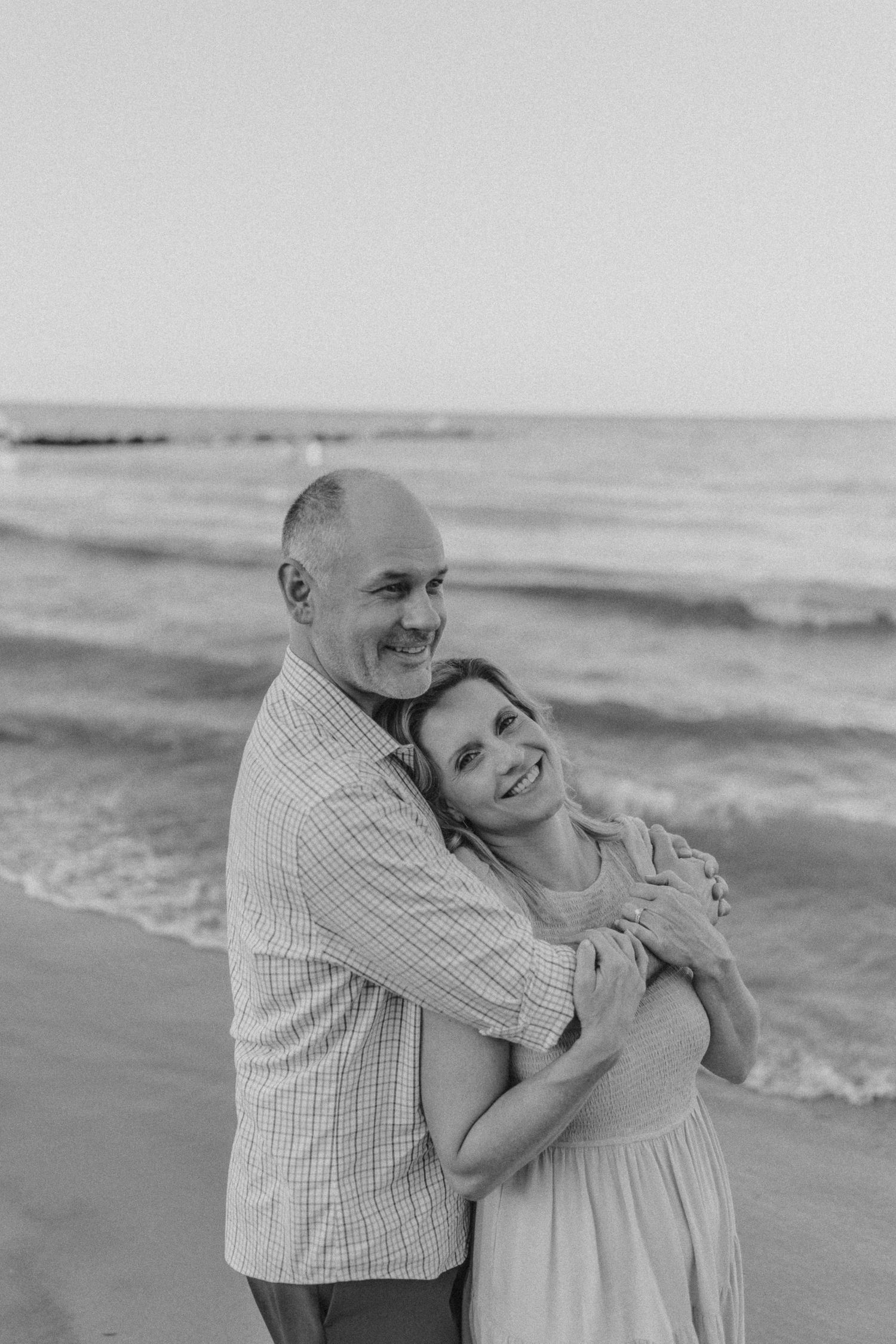 Black and white portrait of a happy couple embracing on the beach.