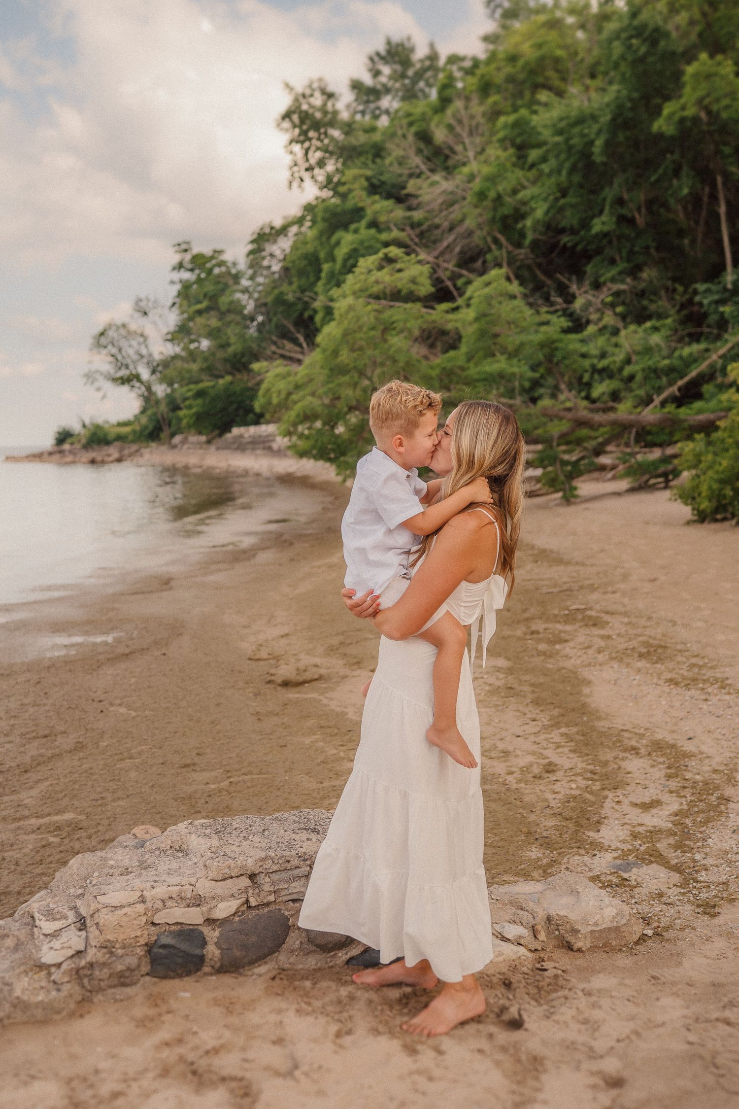 A tender moment shared between parent and child on a scenic beach with lush greenery.