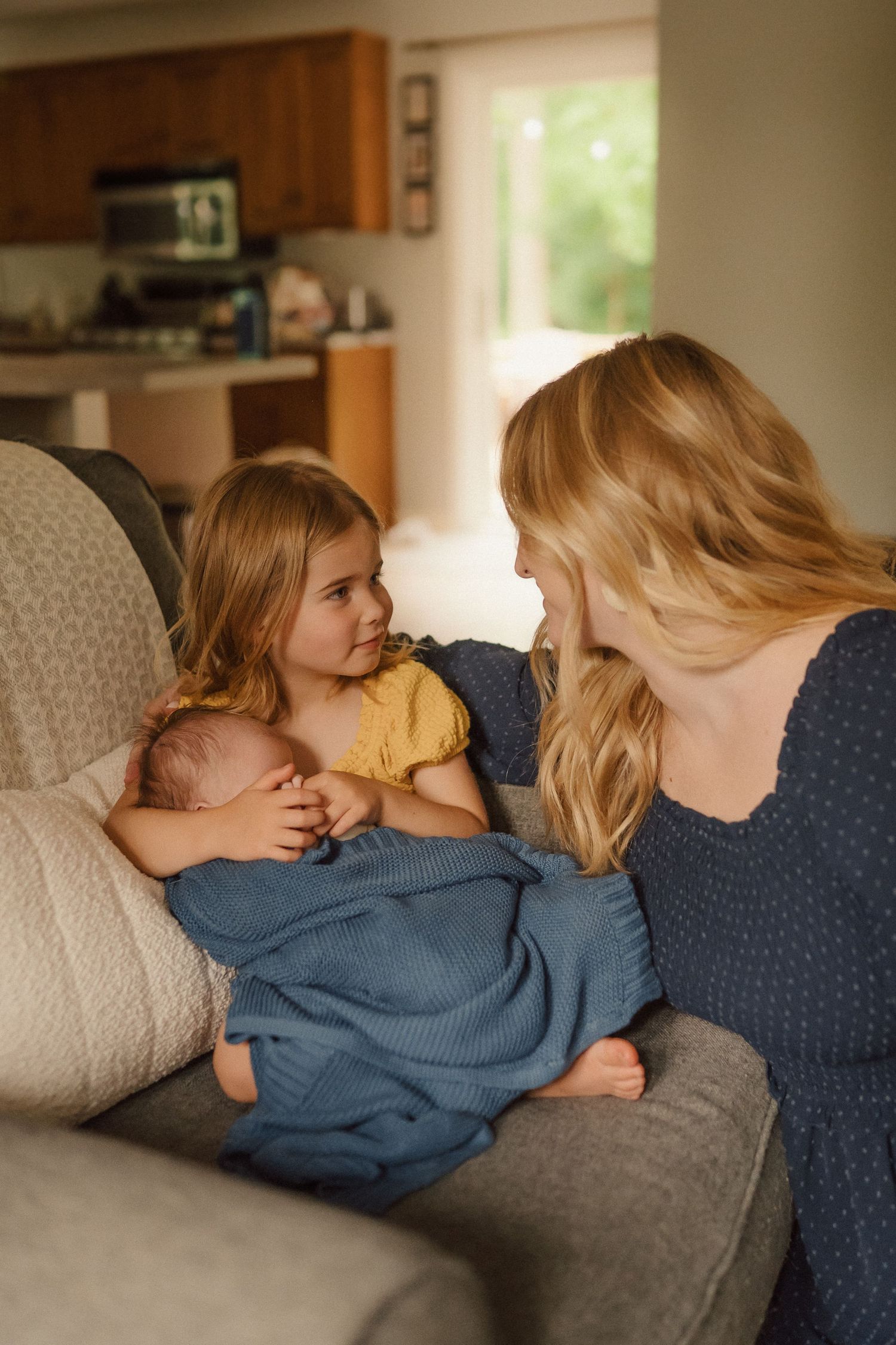 A tender family moment shared on a comfortable couch with an infant wrapped in blue.