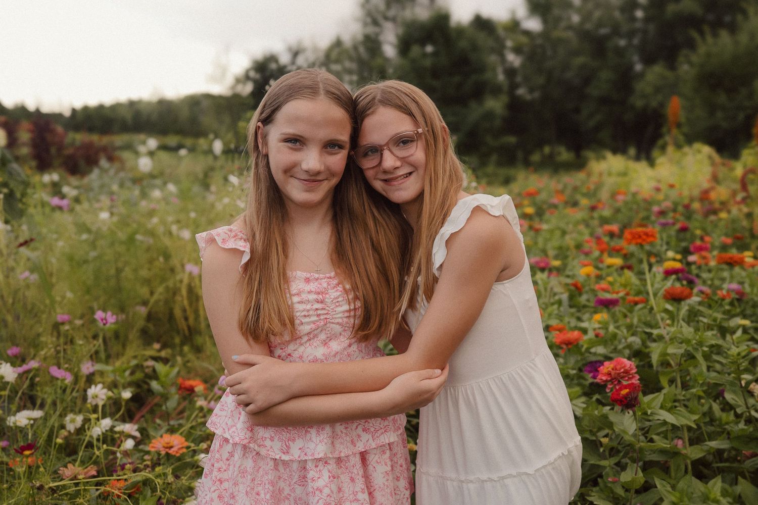 People embrace and smile together in a colorful wildflower field during summer.
