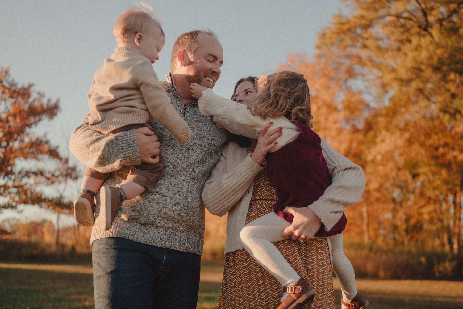 Tender family moments captured against autumn trees with warm golden light.