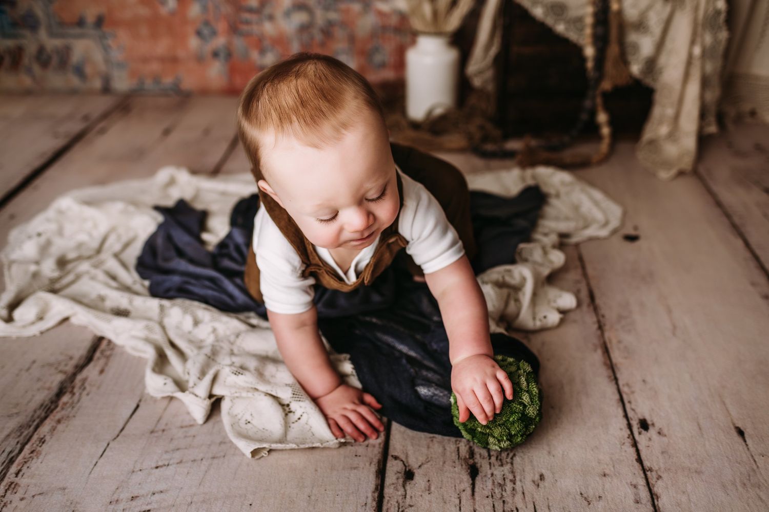 Playing with green decorative prop on rustic wooden floor setting.