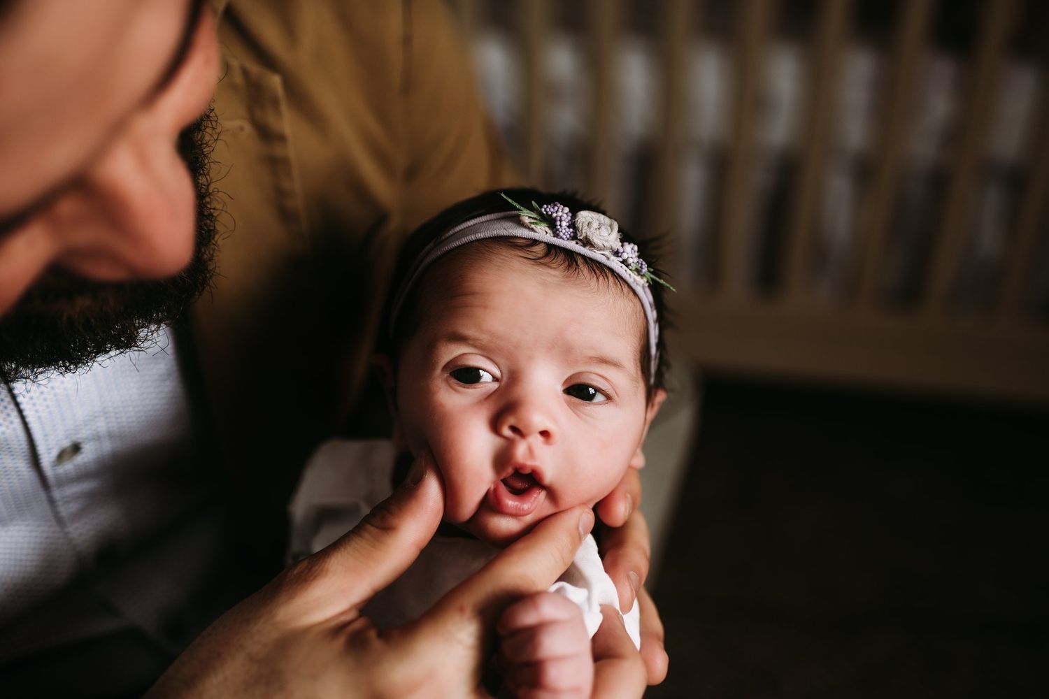 Close-up view of small baby wearing headband in soft lighting.