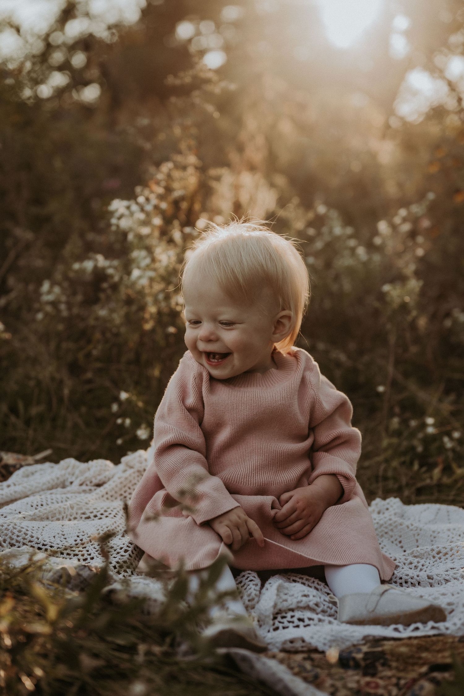 A happy moment on a lace blanket surrounded by golden sunlit foliage.