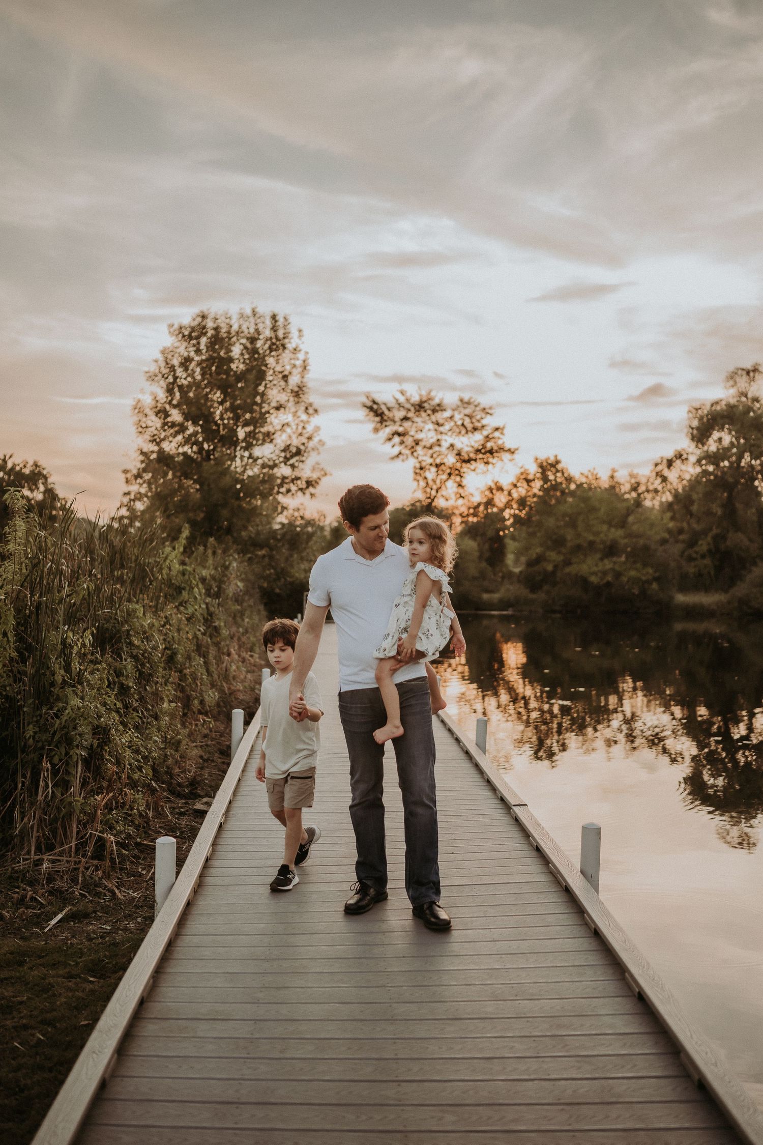 Family walking together on a peaceful boardwalk during golden hour.
