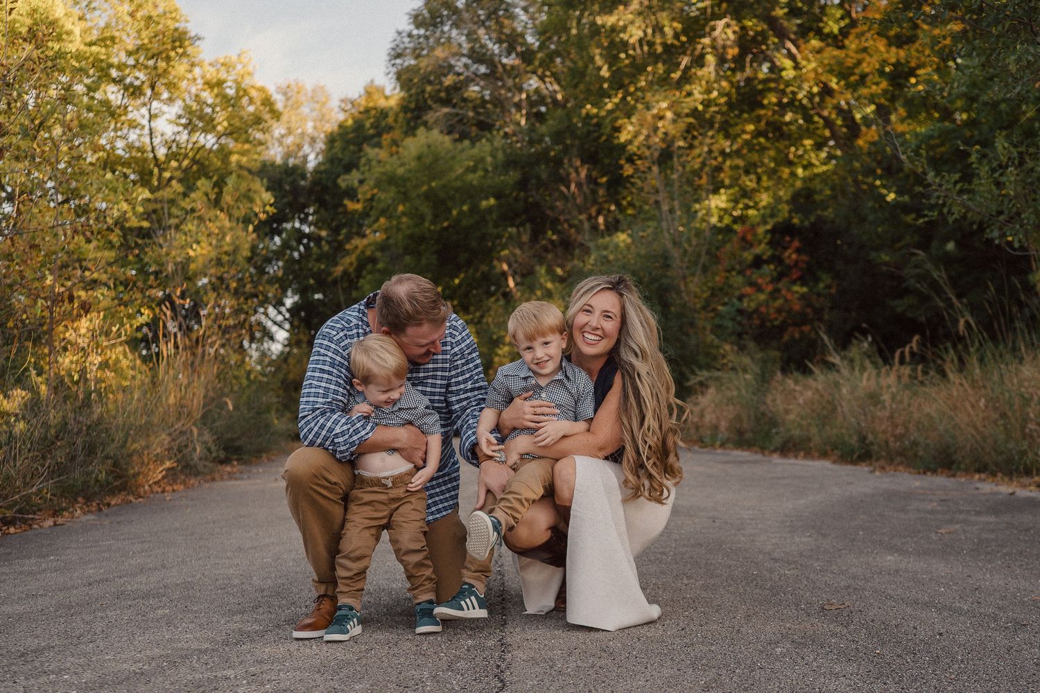 Candid family moments photographed on a natural trail with golden sunlight filtering through trees.