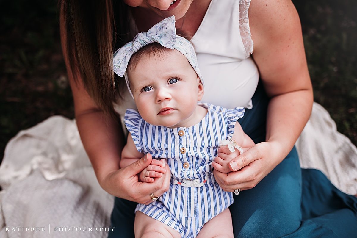 Close-up portrait showing a baby wearing a blue striped outfit with matching headband.