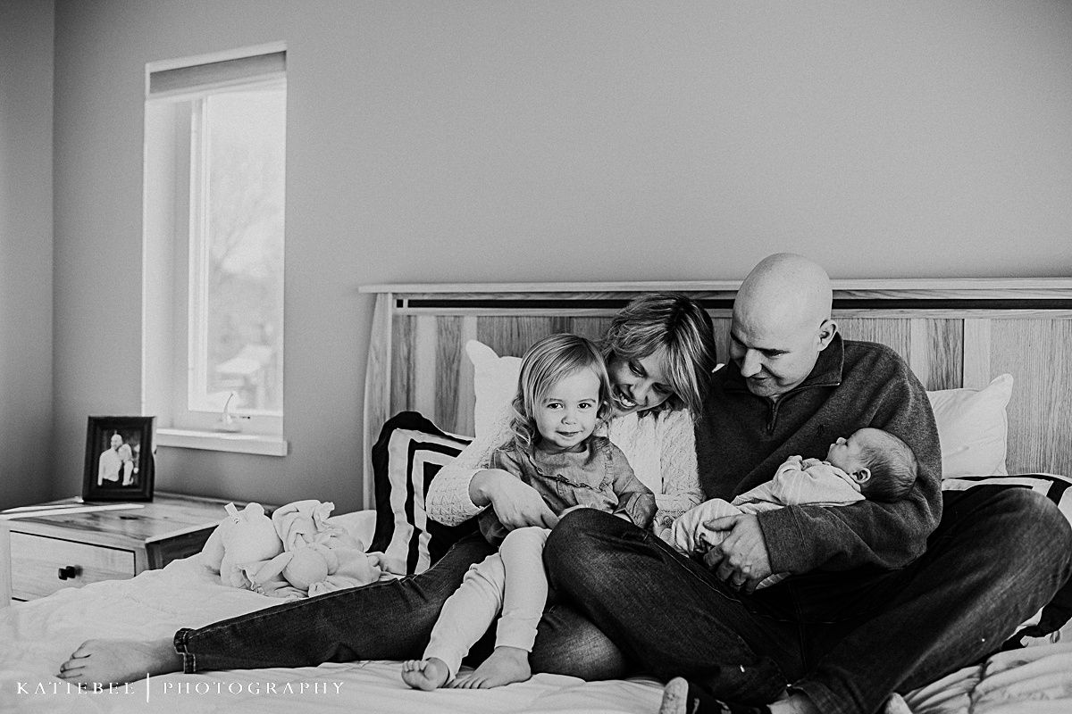 A tender family moment relaxing together on a bed with a newborn baby and toddler.