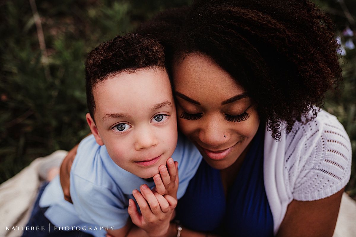 Close-up portrait of mother and child sharing a gentle moment against a natural backdrop.