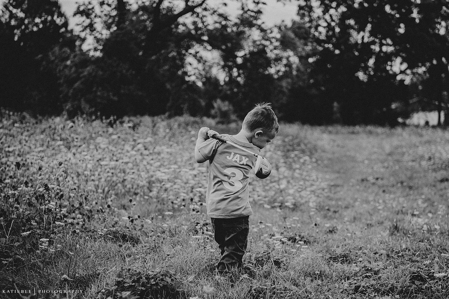A black and white photo of a small child playing in a wildflower meadow at dusk.