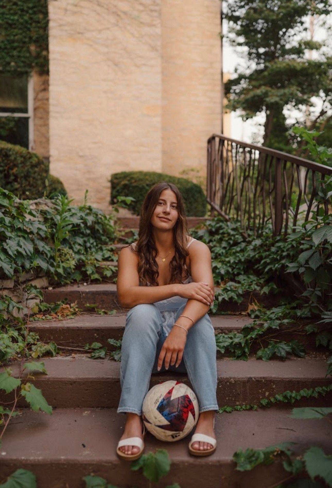 A casual portrait session on rustic wooden steps surrounded by lush greenery.