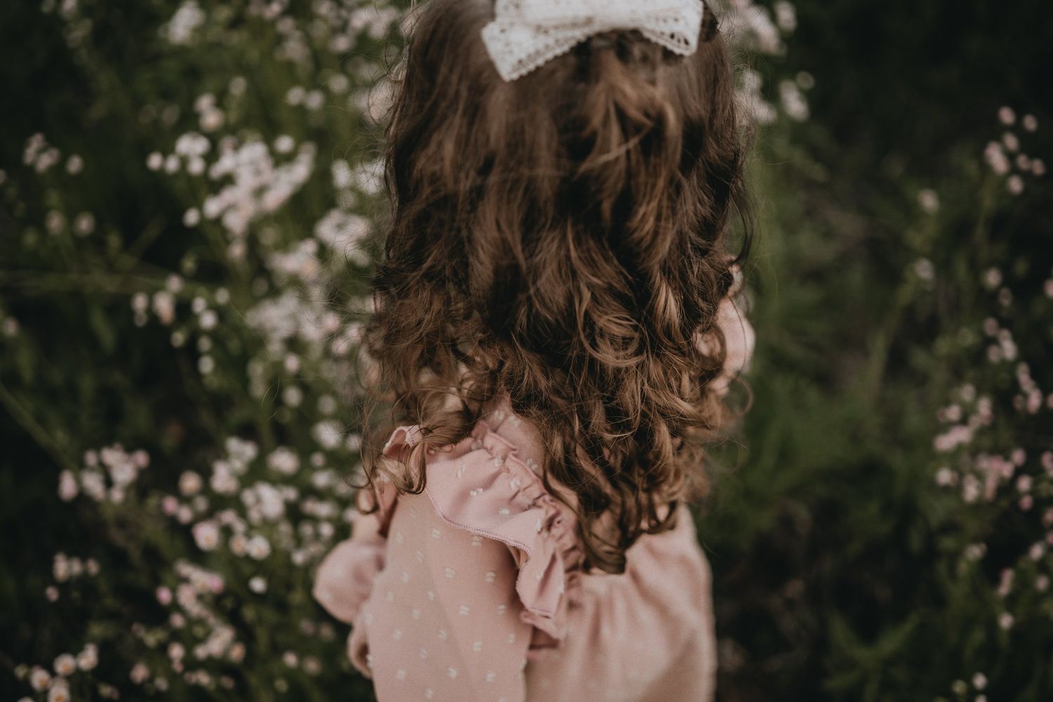Back view portrait showing detailed curls and ruffled dress details.