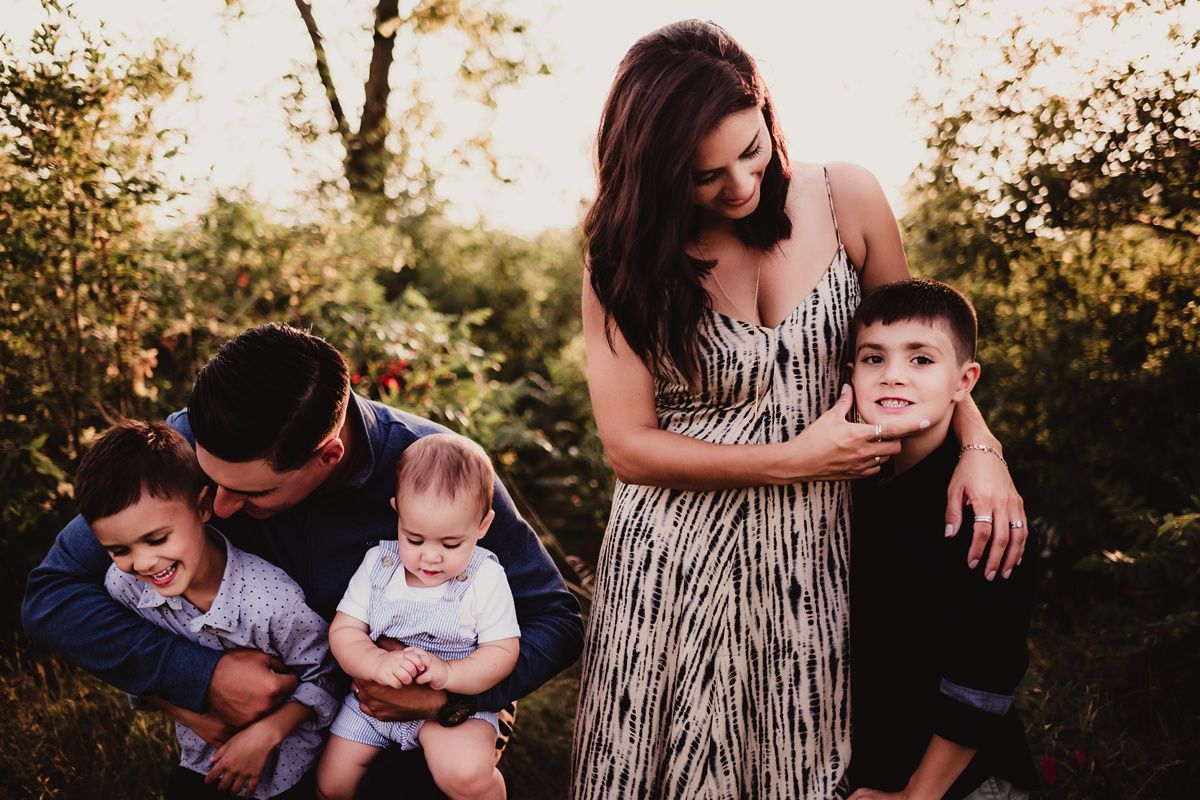 Family portrait with striped dress and casual outfits in natural outdoor setting.