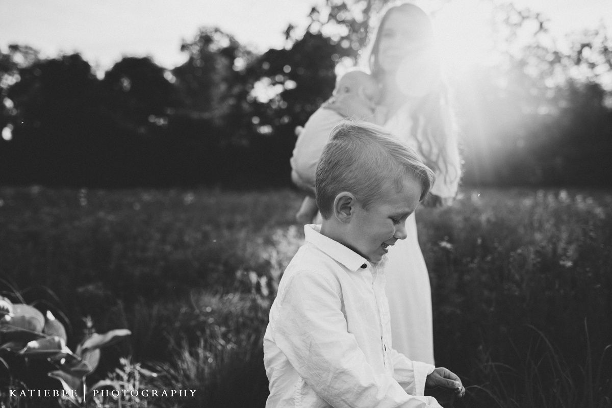 Black and white portrait of child and parent in sunlit field.