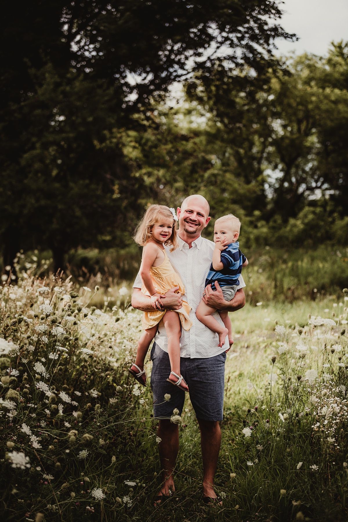 Candid family portrait in a summer meadow filled with wildflowers and natural light.