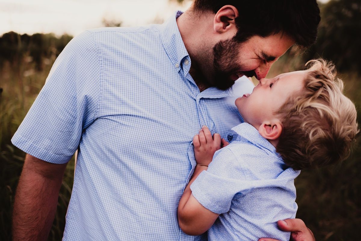 A tender moment of play and laughter shared between parent and child in a sunlit field.