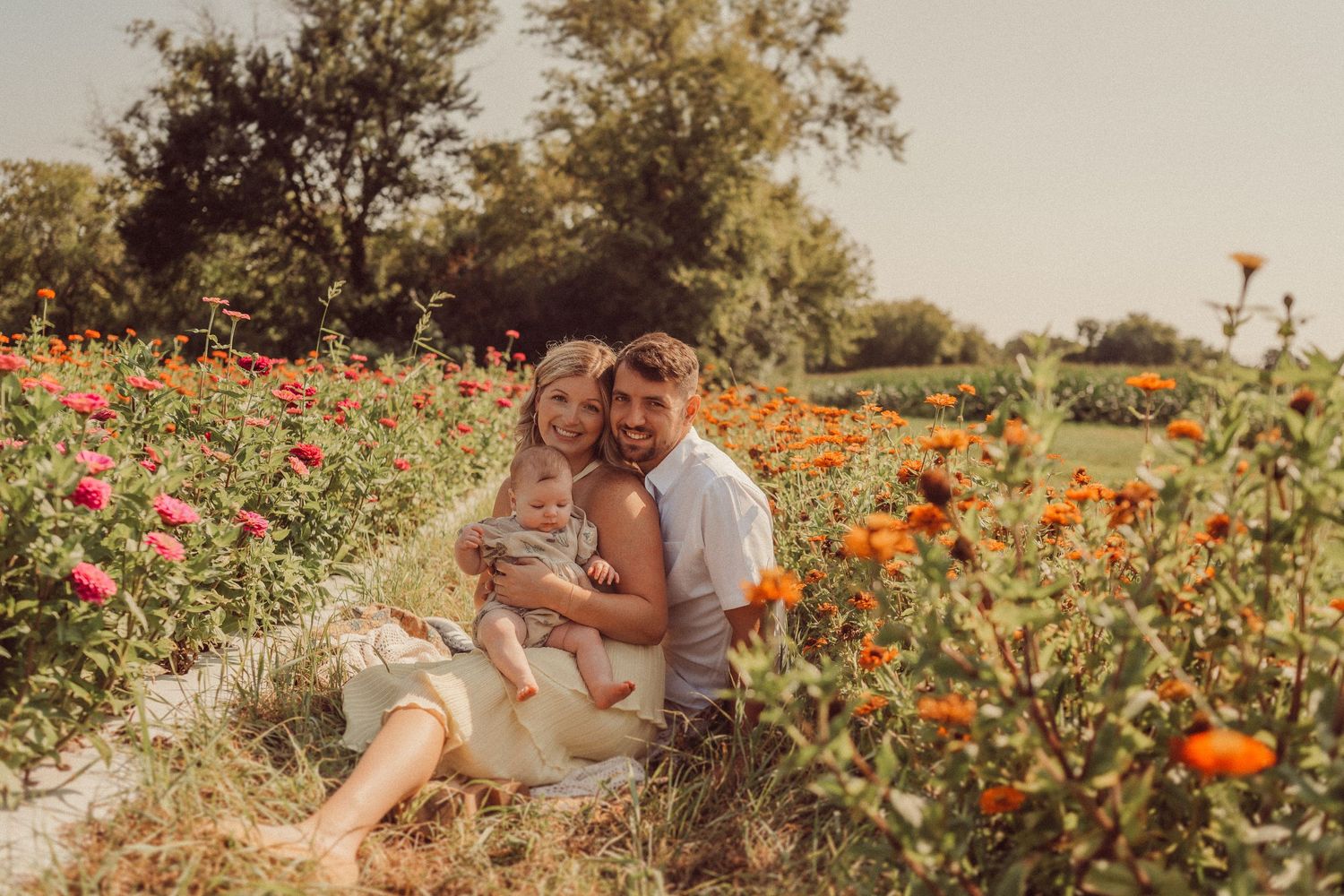 A family portrait taken in a garden filled with colorful summer flowers.