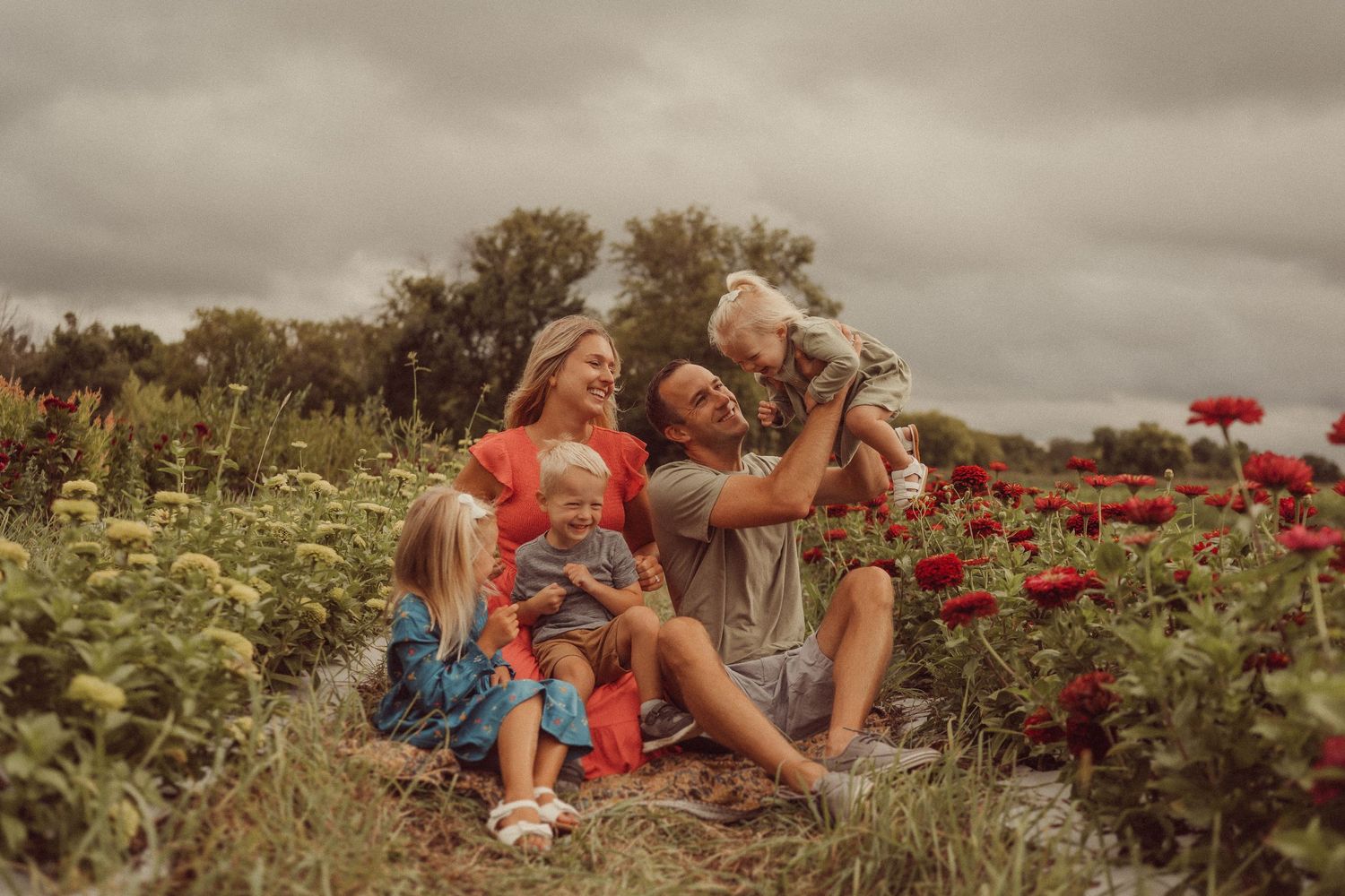 Happy family moment captured in a garden filled with bright red blooms.