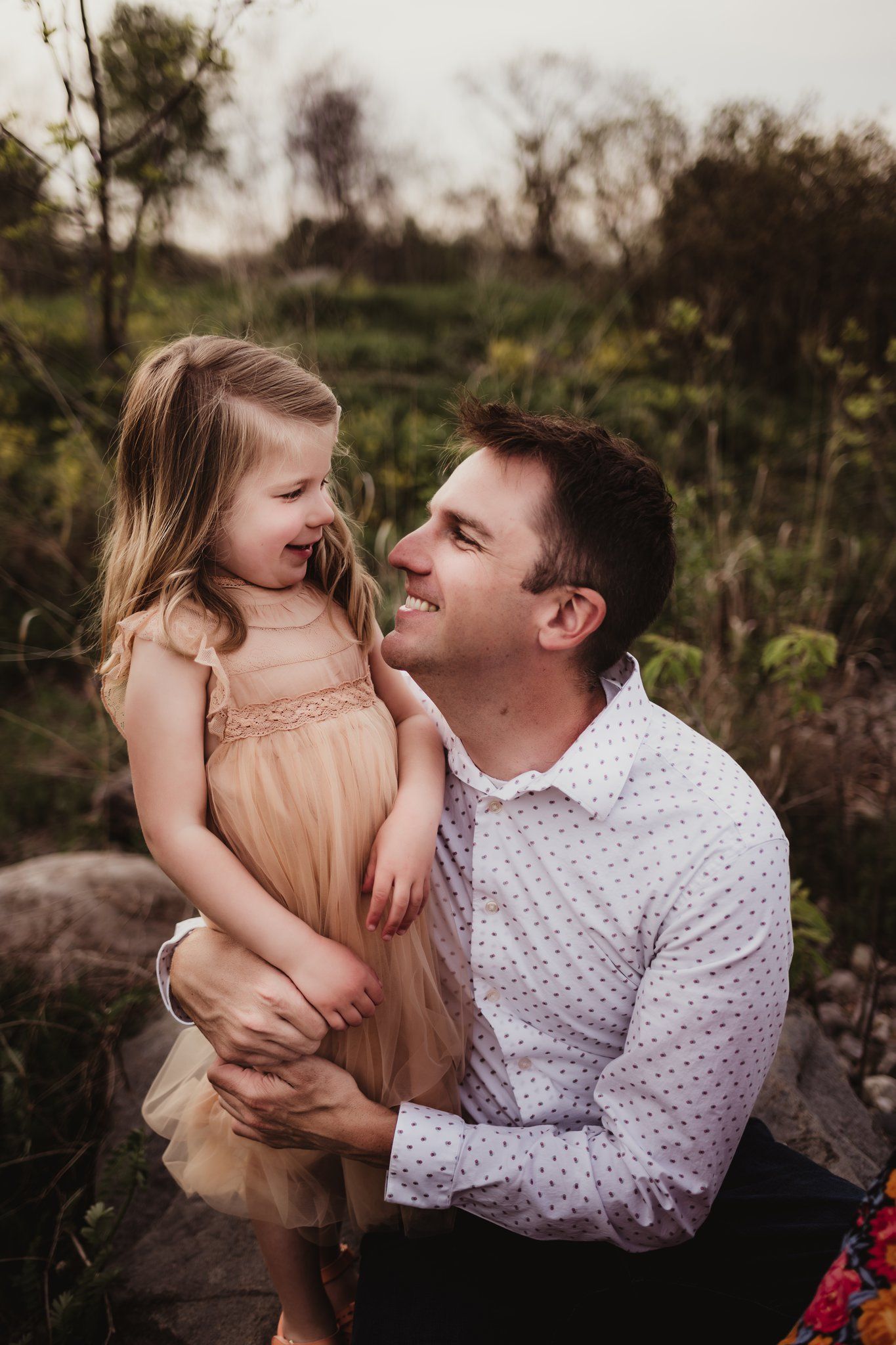 Heartwarming moment captured between parent and child during outdoor photoshoot on rocky terrain.