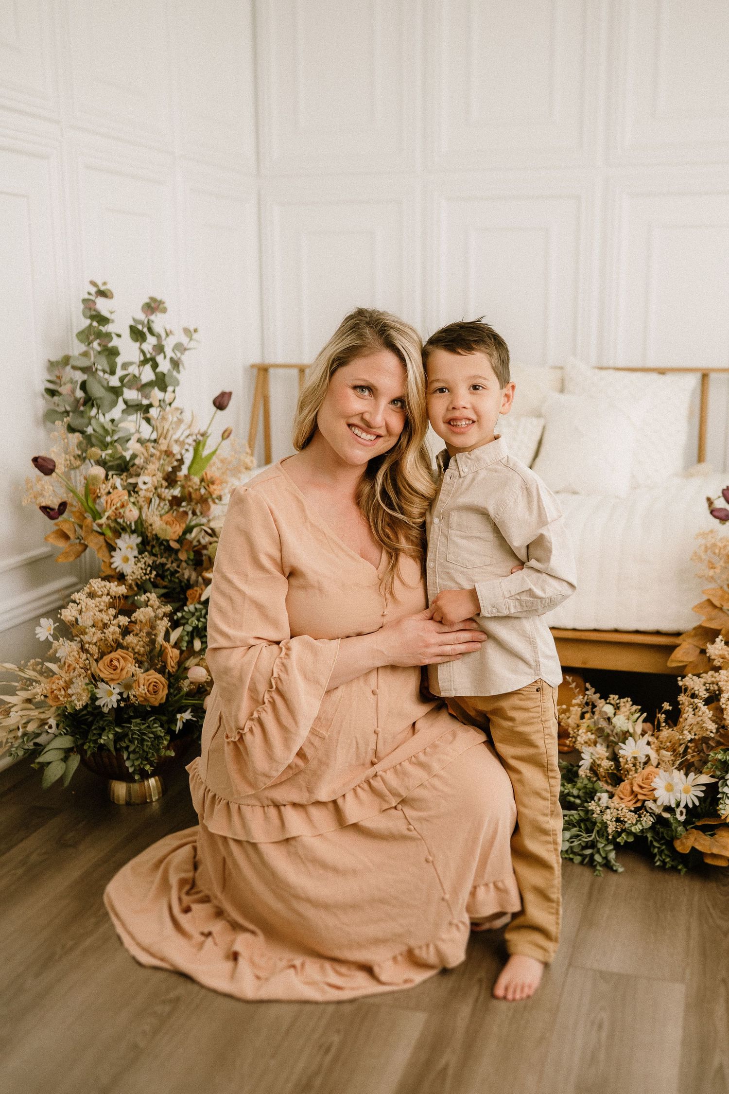 A tender portrait of a parent and child embracing in a softly lit room with floral arrangements and wooden furniture.