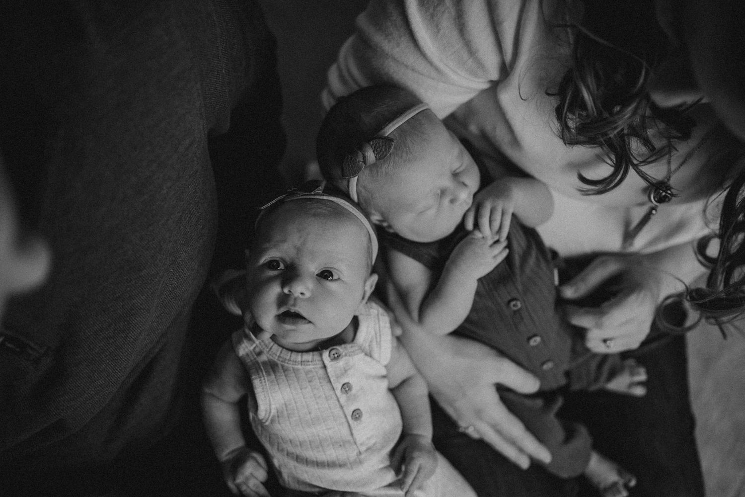 Black and white photo of parents with babies resting on couch.