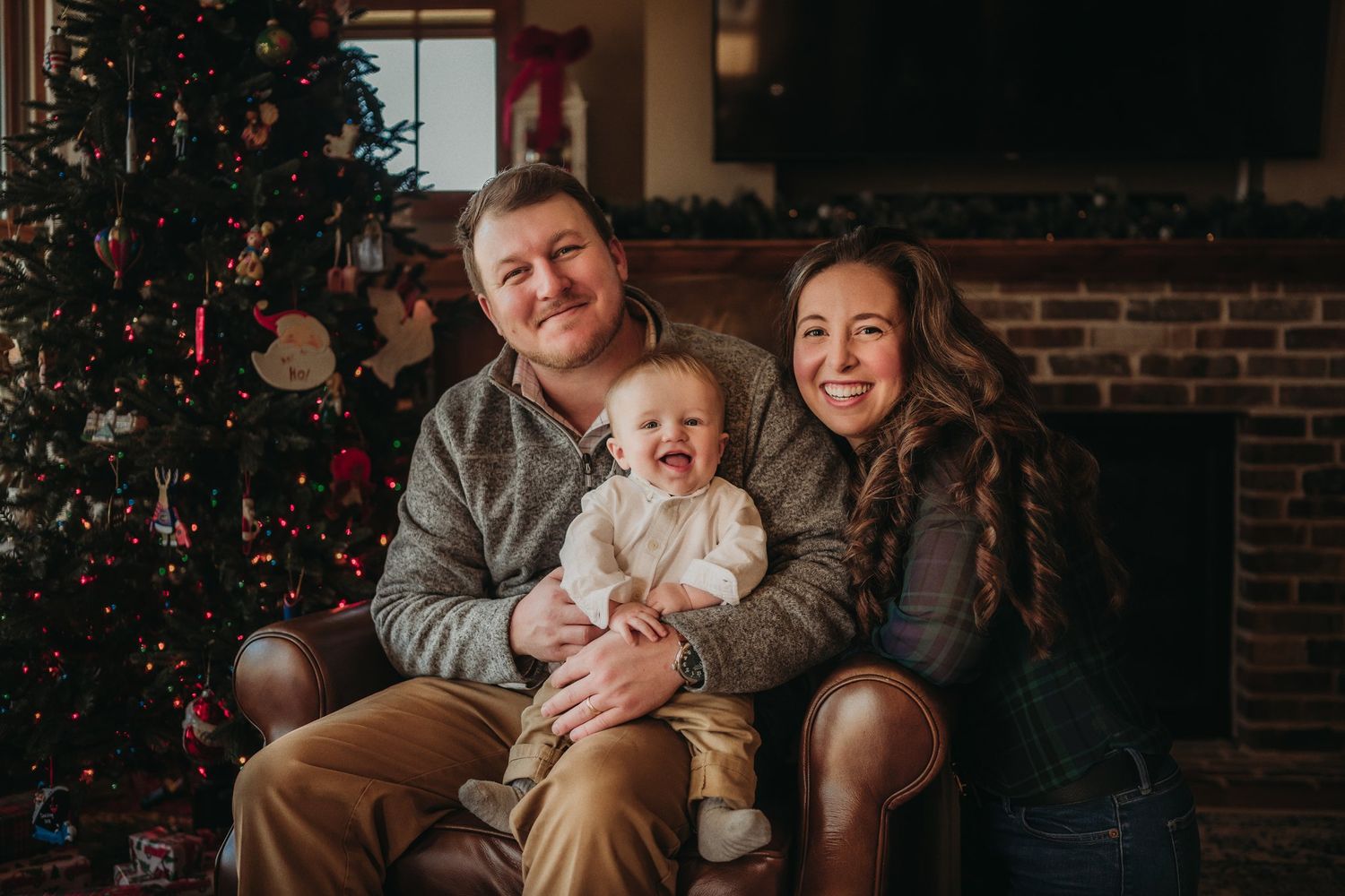A family shares a joyful moment together on a leather couch near their Christmas tree.