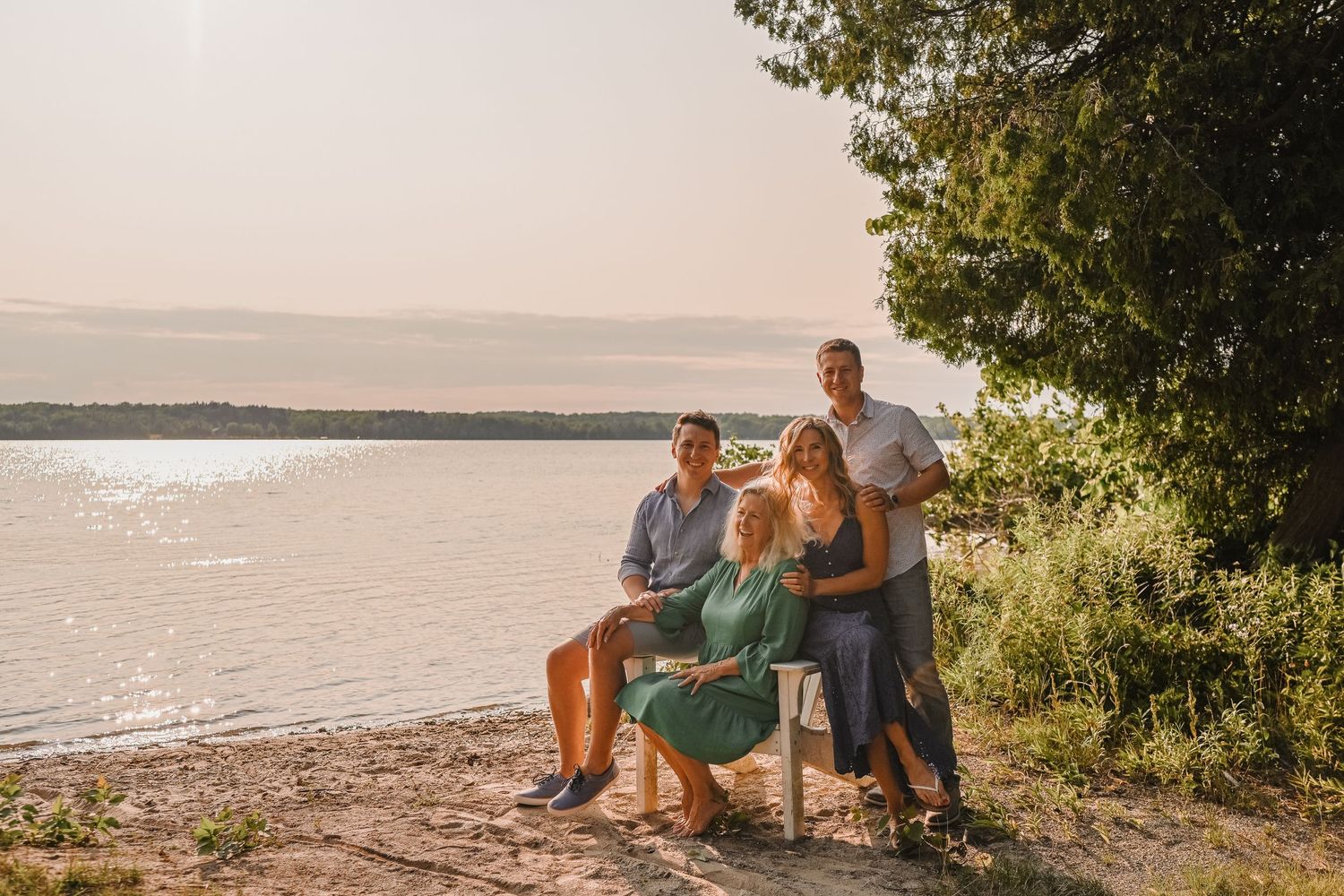 Family enjoying sunset together on a lakeside beach with water views.