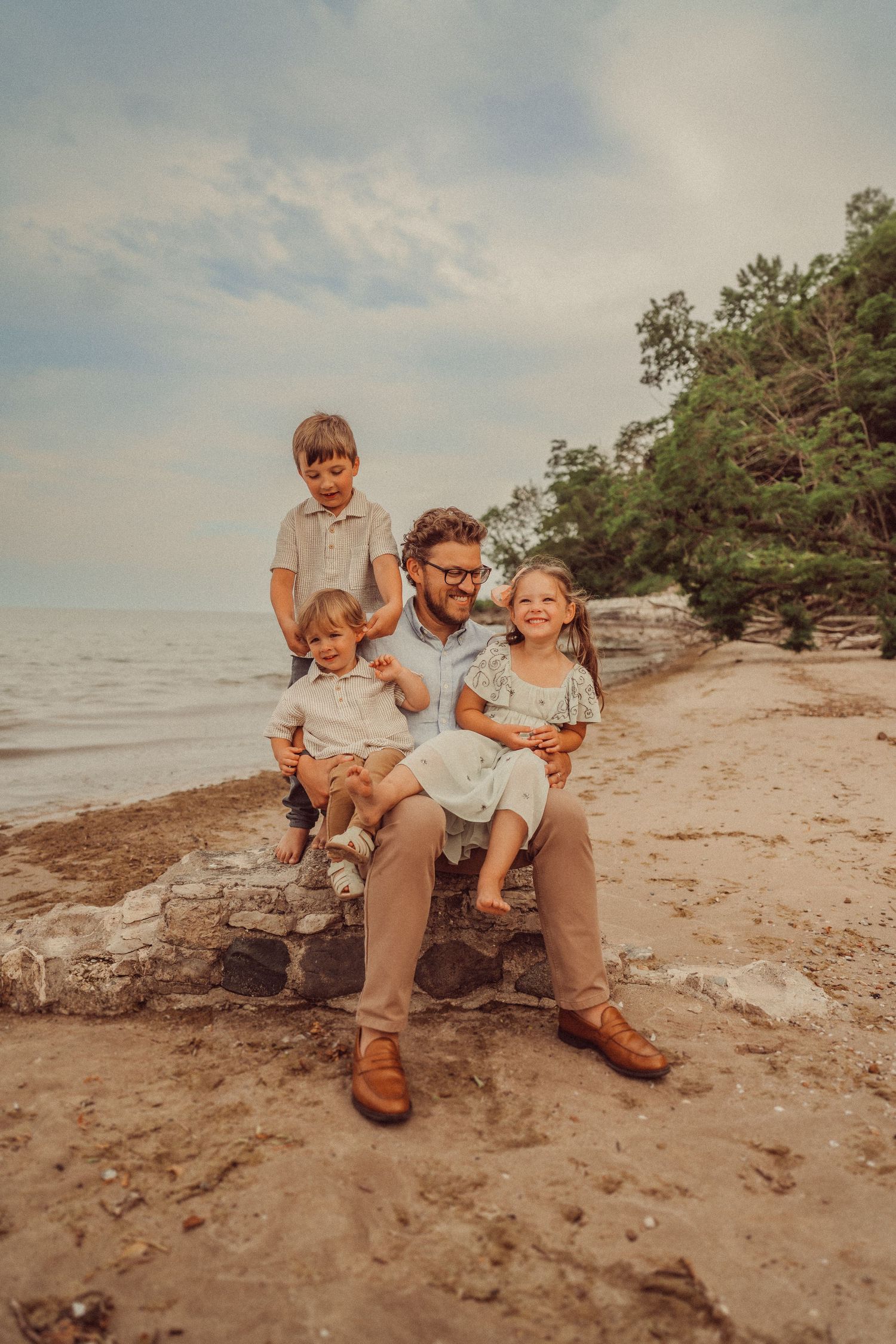A group sits together on rocky beach outcropping during golden hour.
