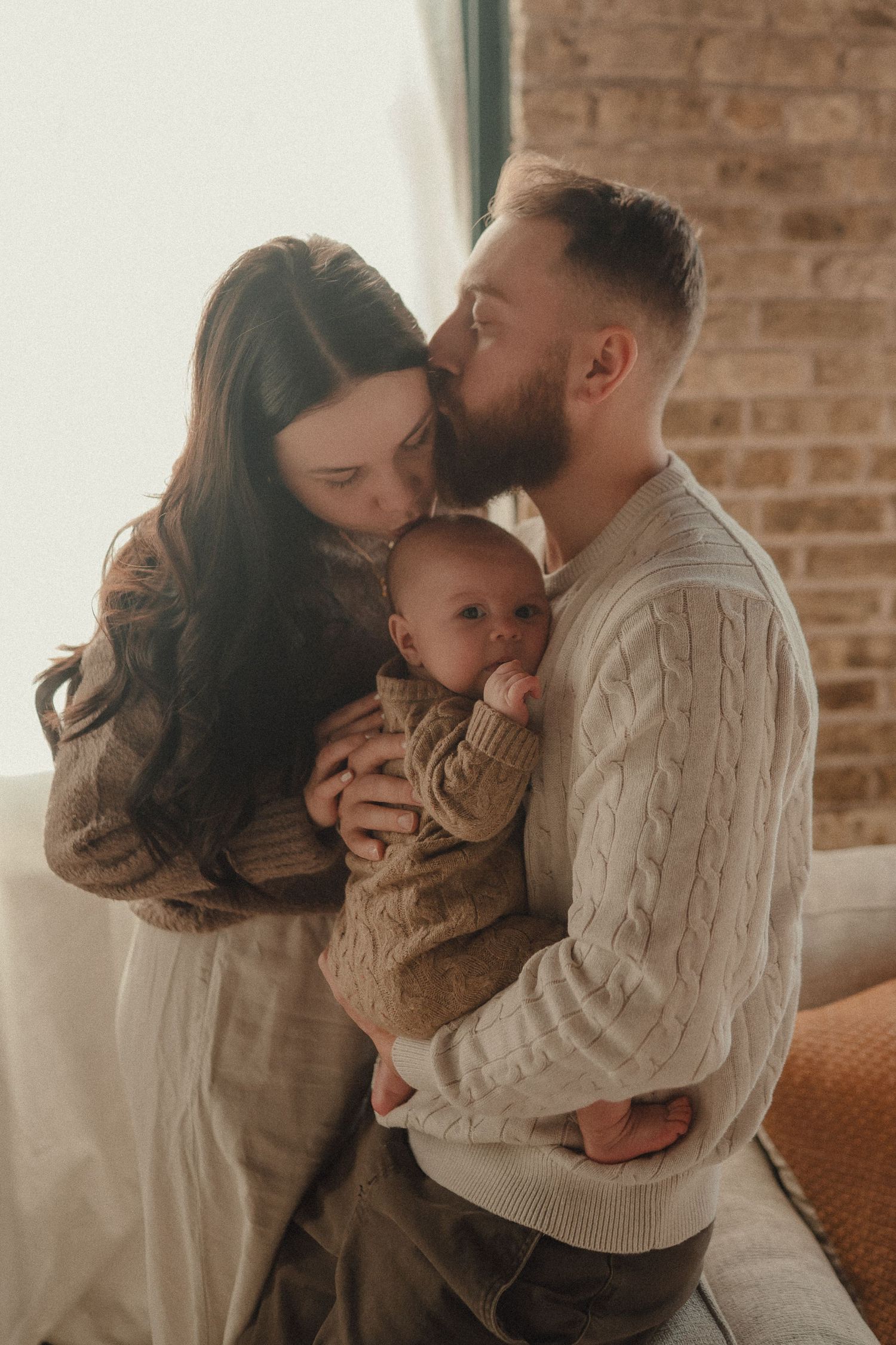 Cozy family portrait session featuring neutral knit sweaters and intimate moments in natural window light.
