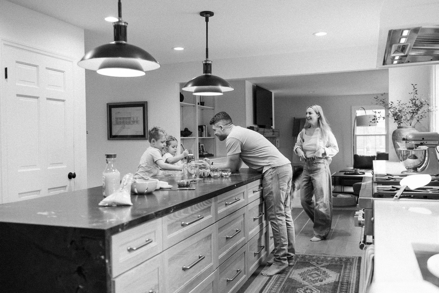 Black and white photo of a family gathered around a kitchen island in a modern home.