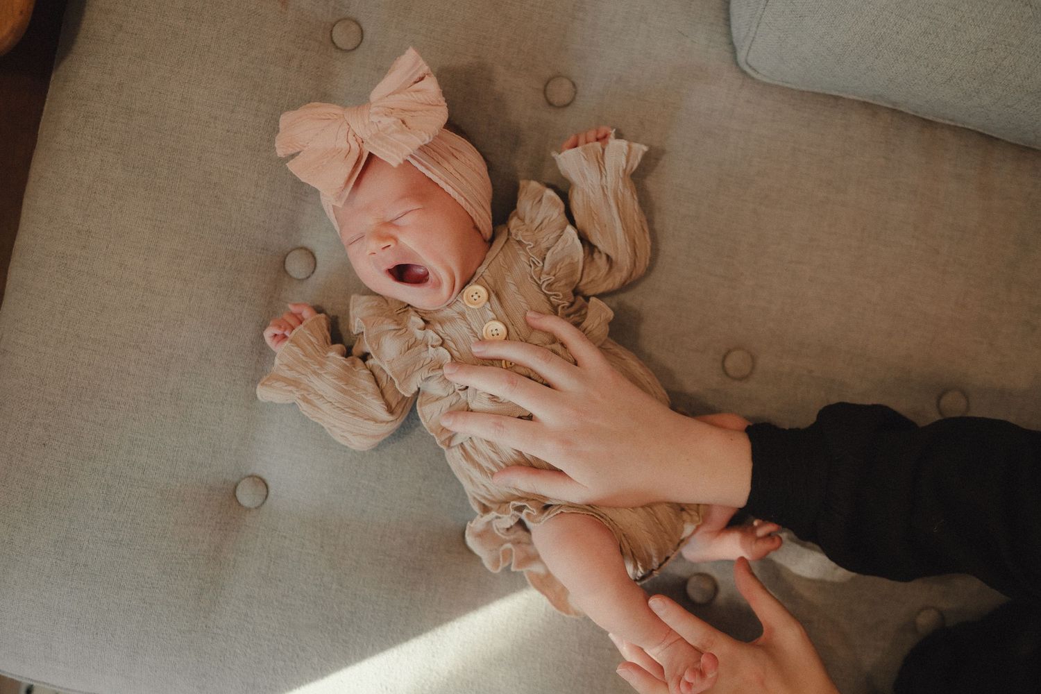 Close-up shots of hands holding and cradling a small infant in soft natural light.