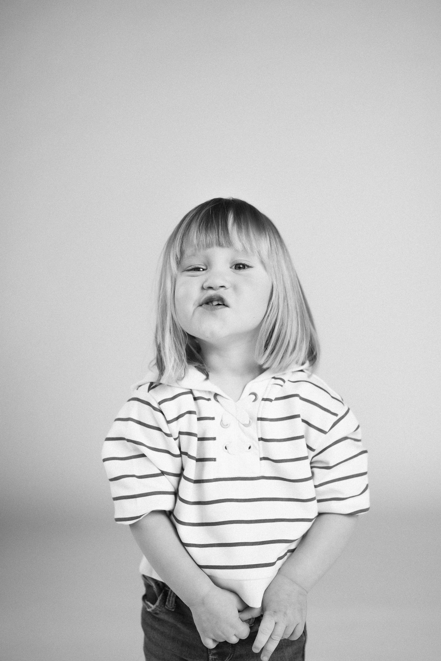 A series of black and white portraits showing a child in a striped polo shirt making playful expressions.