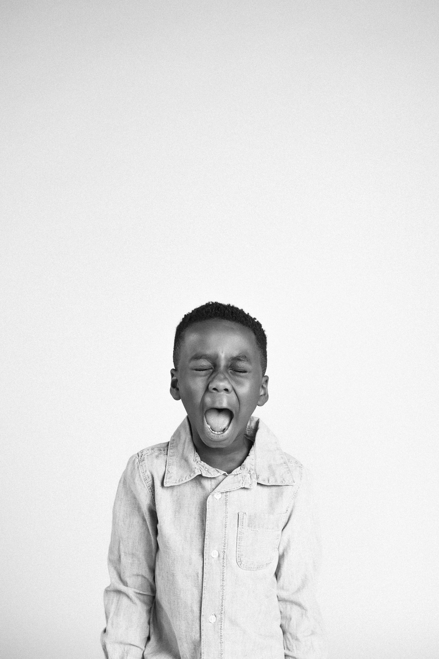 A series of three black and white photos showing a young child in a white shirt expressing different emotions.