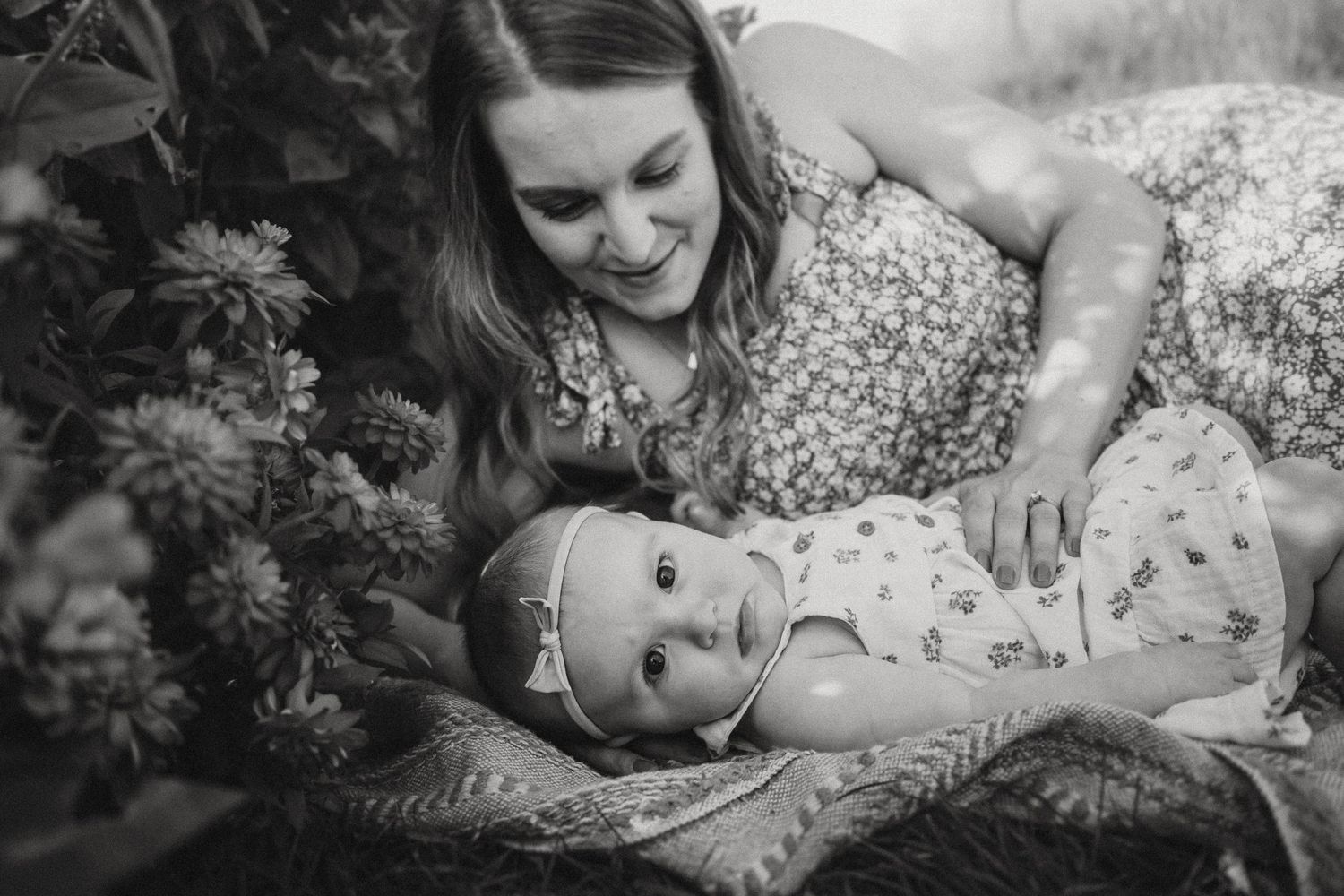 Black and white portrait showing tender moment among garden flowers.