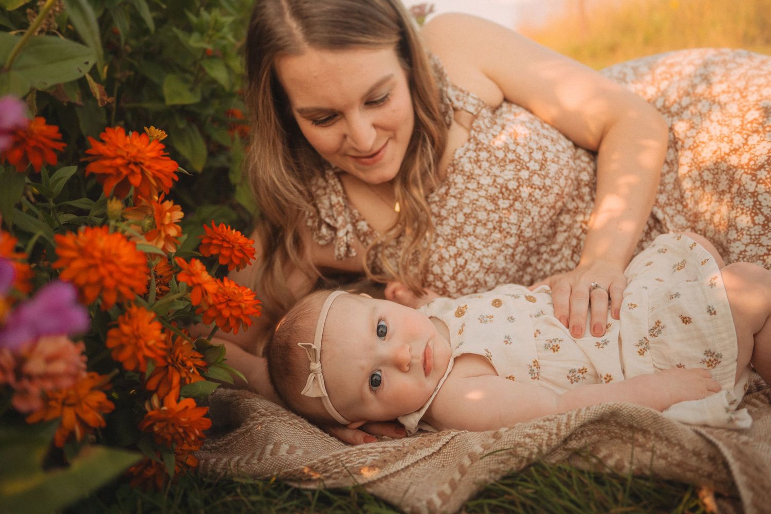 A tender moment between parent and baby among vibrant orange and purple flowers.