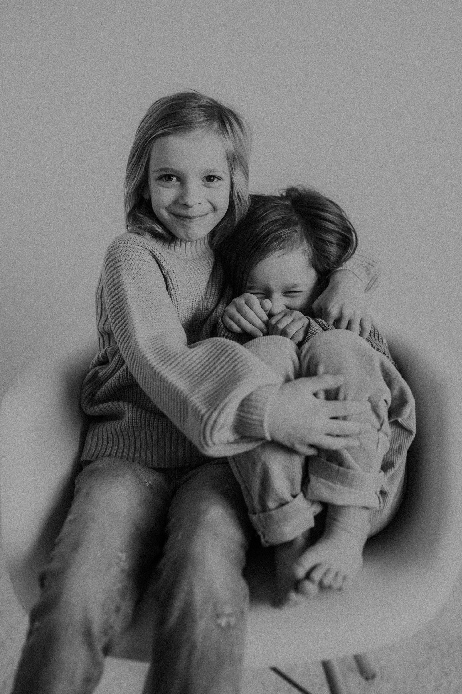 Two people sharing a candid moment while sitting in a modern white chair.
