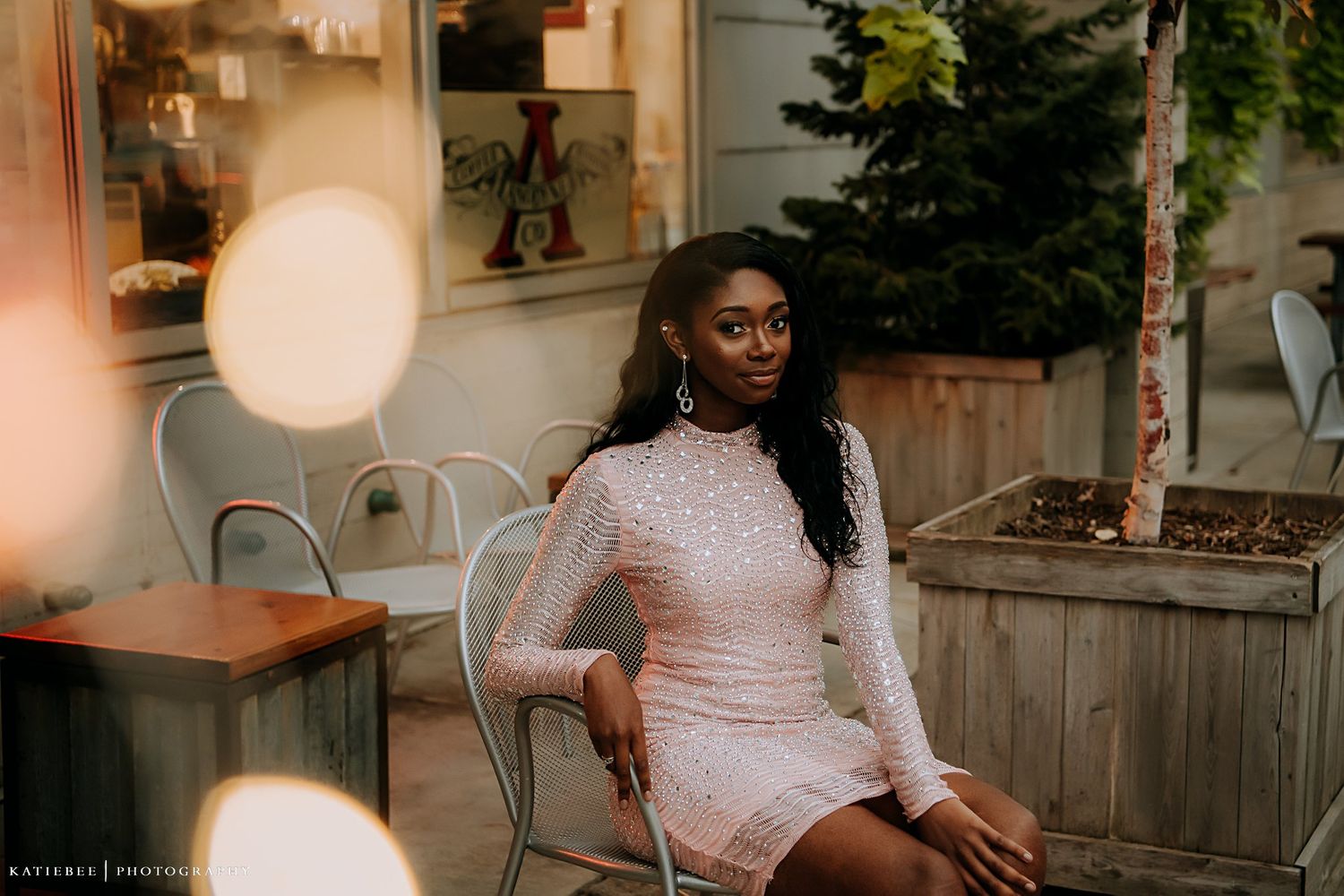 Indoor portrait in light pink dress with soft ambient lighting and rustic decor.
