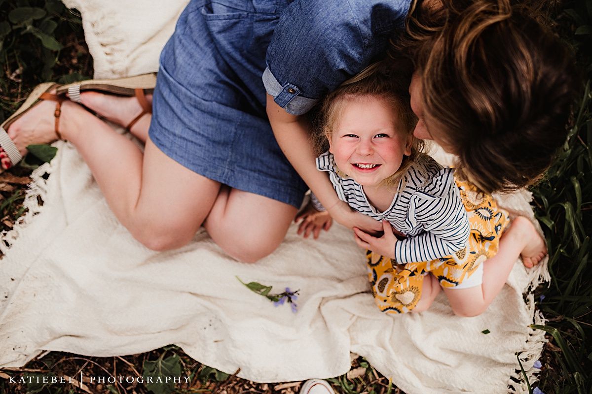 Two people share a joyful moment while sitting on a white blanket outdoors.