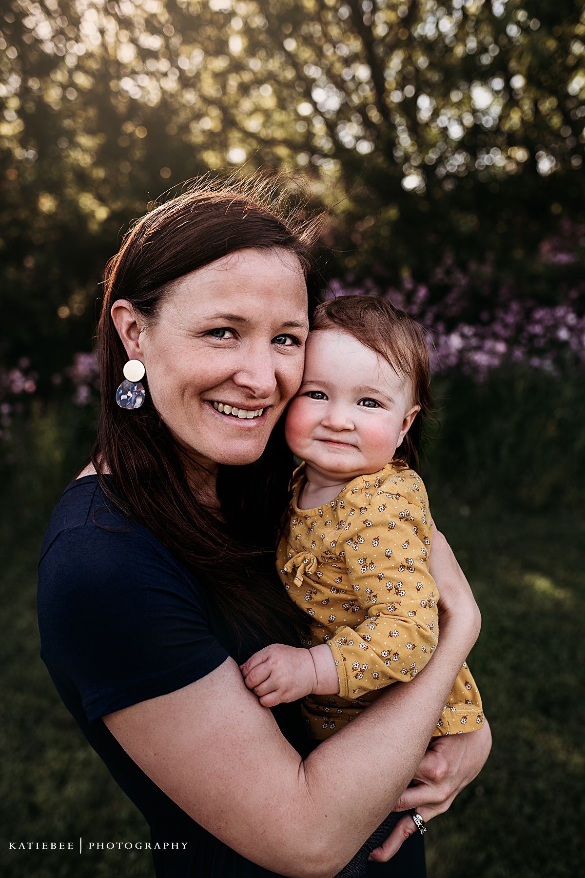 Sweet portrait captured at golden hour with purple wildflowers creating a dreamy backdrop.