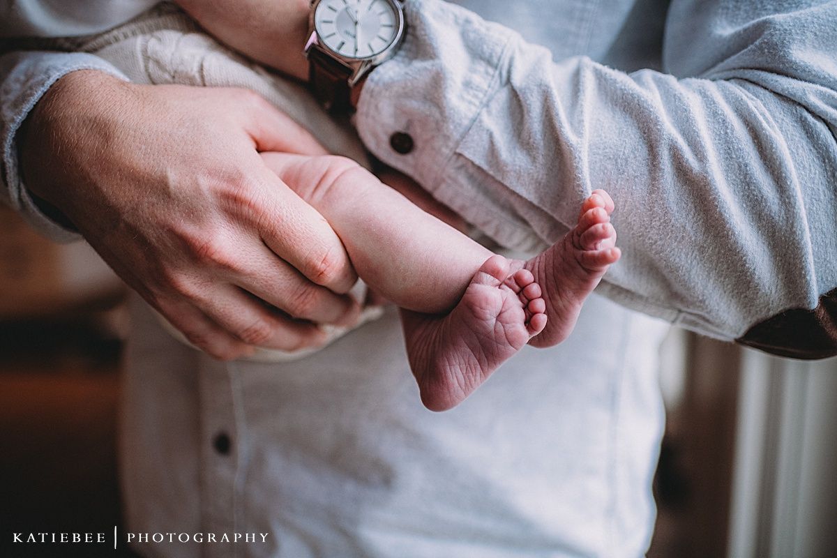 Close-up photograph of hands gently holding tiny baby feet.