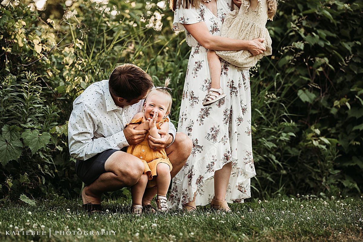Playful family moment captured in garden setting.