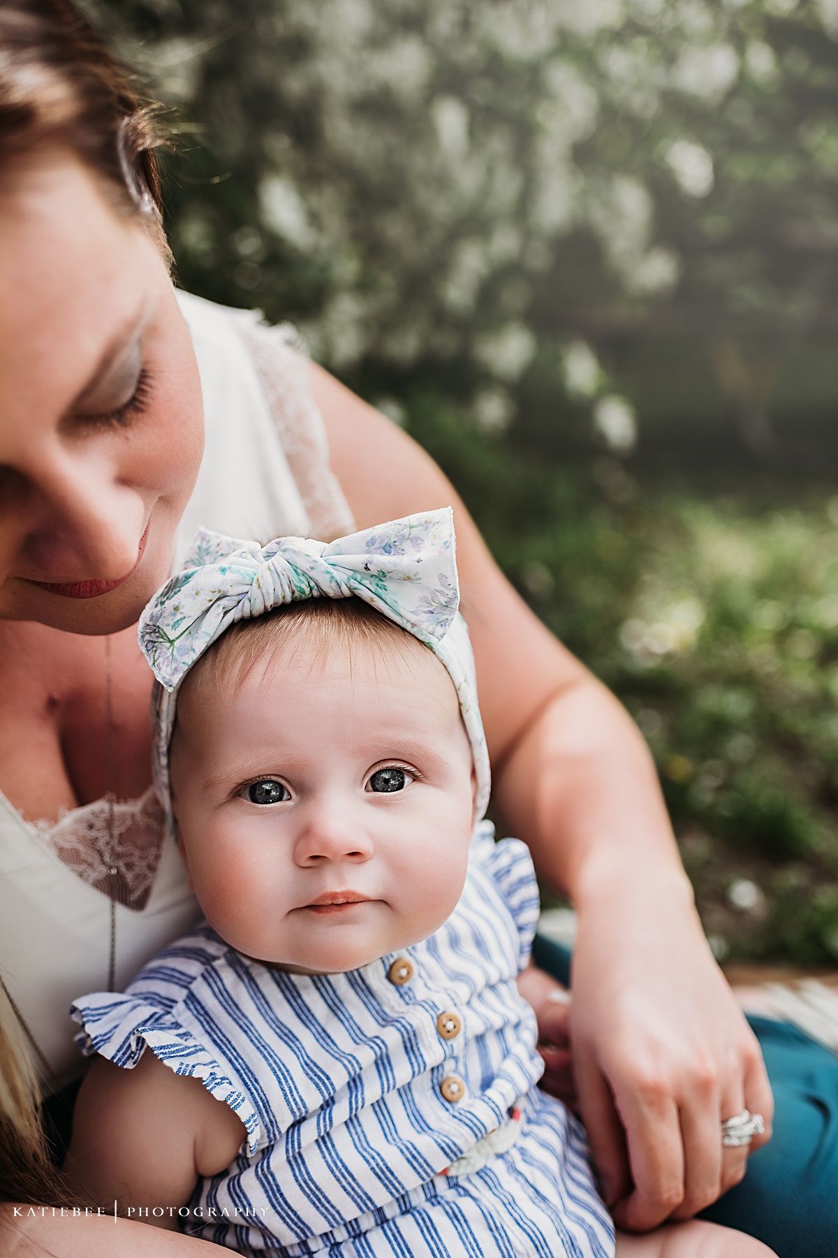 Intimate close-up portrait showing parent and child against a soft bokeh background of white flowers.