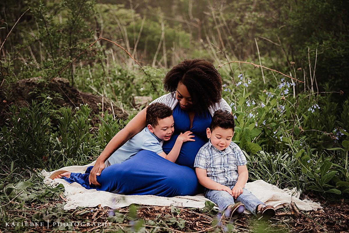 Mother and children relaxing together on a blanket during an outdoor photo session.