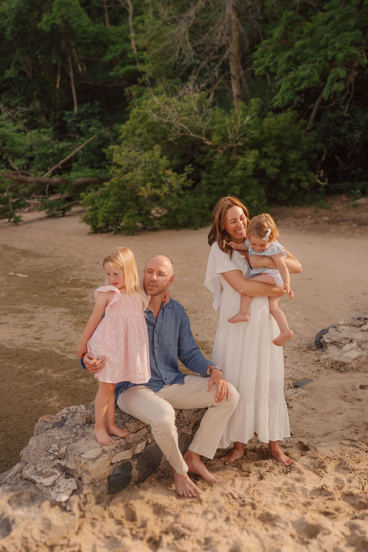 Beautiful beach family portrait with everyone dressed in coordinating blue, white and pink outfits.