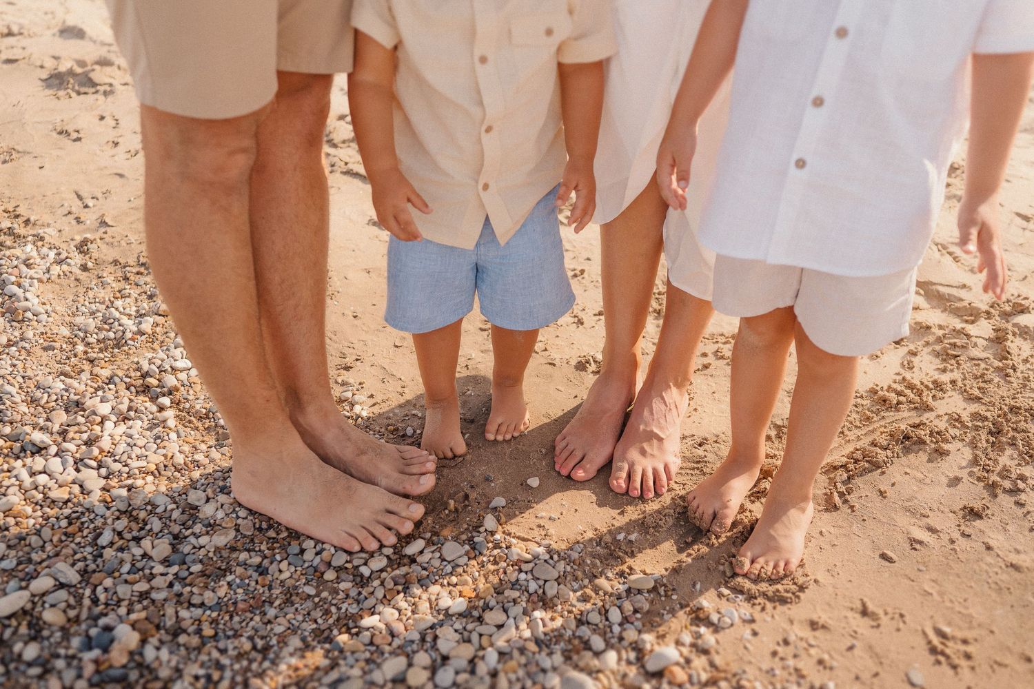 Close-up shot of casual beach attire showing white and beige clothing against sandy backdrop.