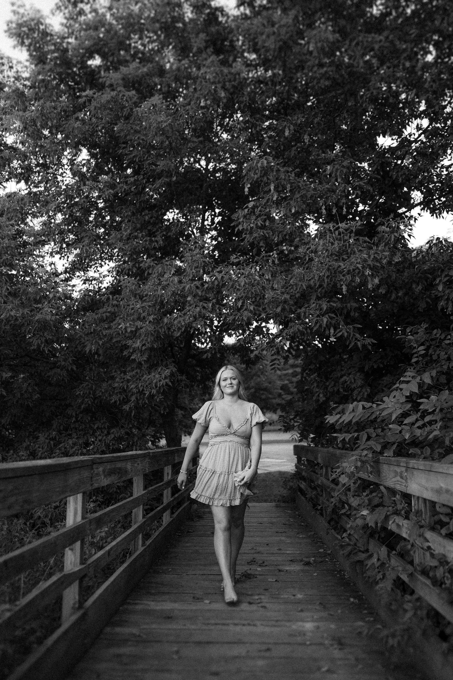 Black and white photograph of a wooden boardwalk surrounded by dense tree canopy.