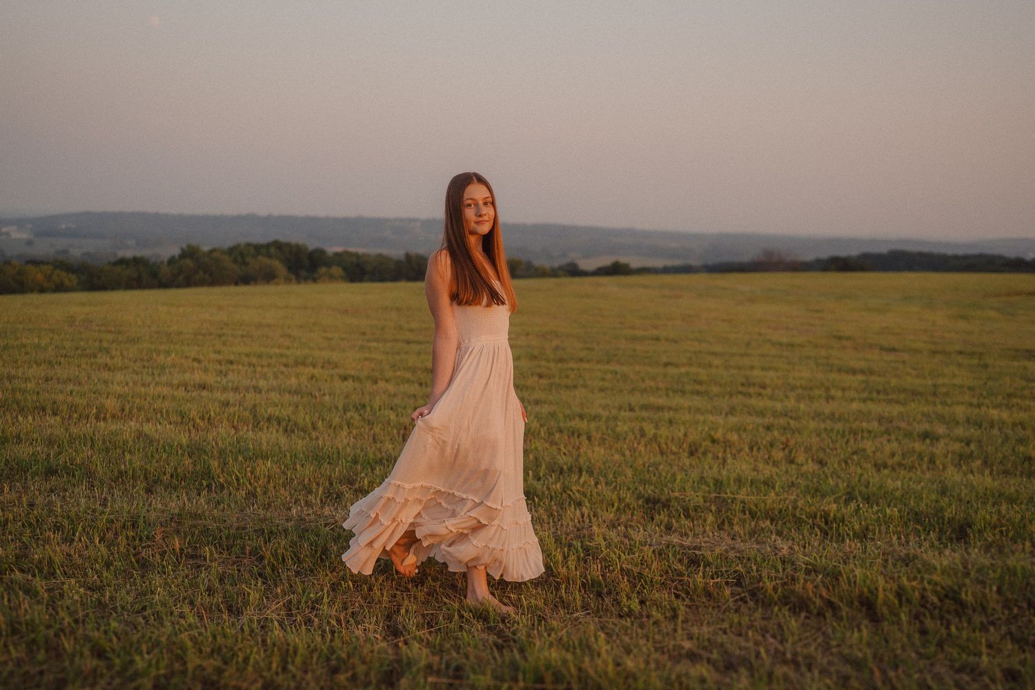 Dreamy sunset portraits in a golden wheat field showing a light flowy dress against the warm evening sky.