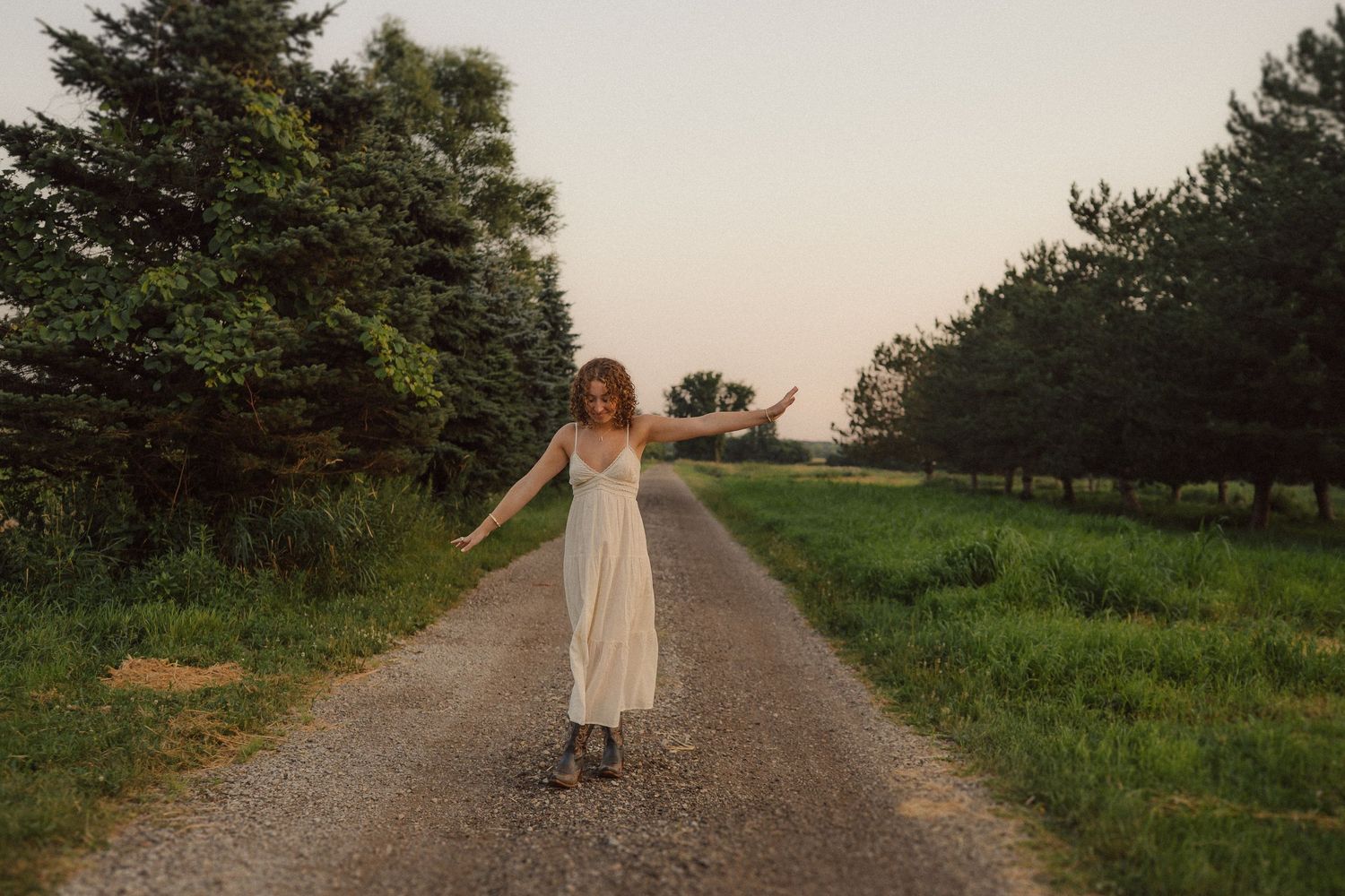Ethereal shots of someone walking along a rural path surrounded by evergreen trees at dusk.